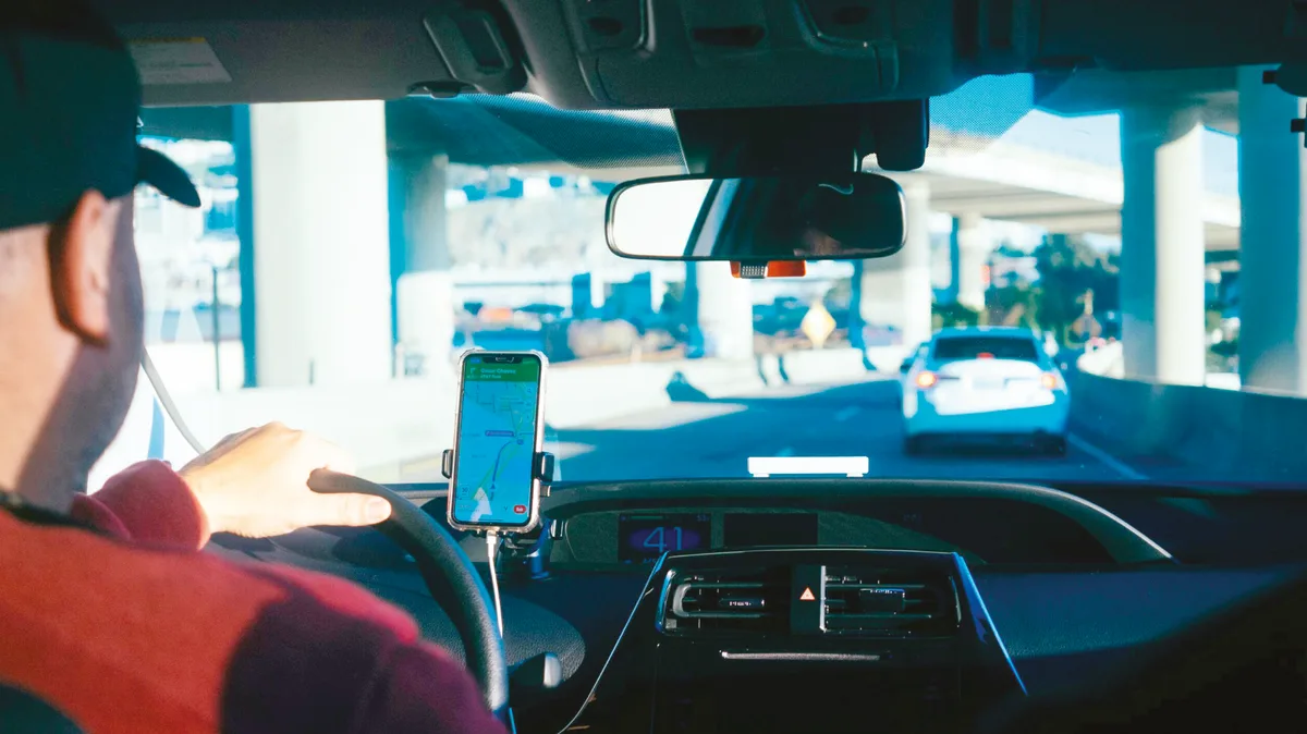 Conducteur au volant consultant une application de navigation sur son smartphone fixé au tableau de bord